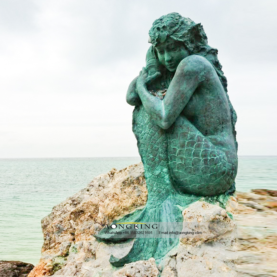 Bronze mermaid sitting on the beach