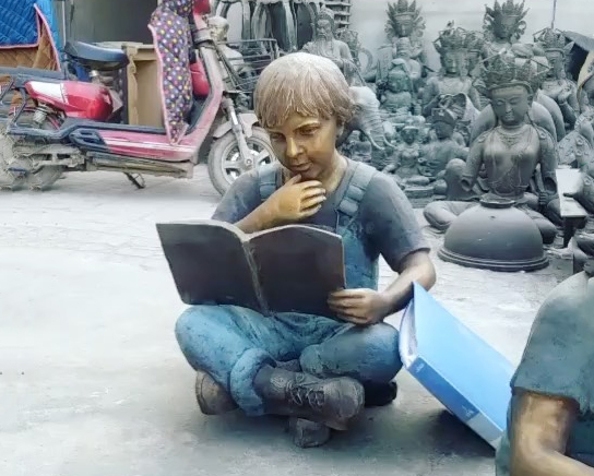child reading book garden statue