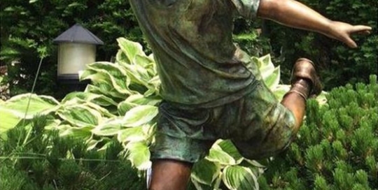 bronze boy playing football sculpture