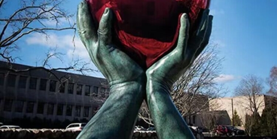 stainless steel hands hold heart sculpture