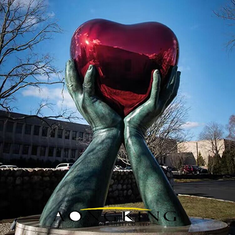 stainless steel hands hold heart sculpture